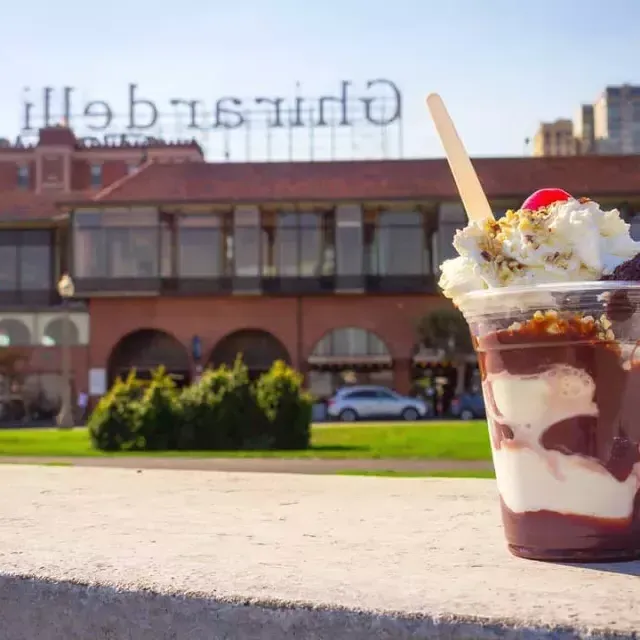 Une coupe glacée au chocolat se trouve au premier plan avec la place Ghirardelli en arrière-plan.